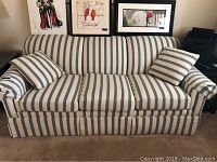 Front view of the sofa showing the blue and white vertical stripe fabric and two matching cushions on arms.