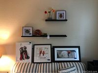 Photo of three art prints displayed on wall shelves and couch backrest showing shoe, bird, and abstract artworks.