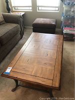 Rectangular wood coffee table with decorative top surface, positioned on carpet near a couch.