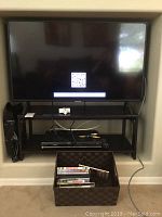 Samsung 40-inch TV on stand with remote and cables