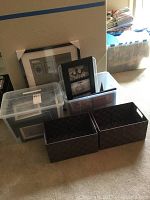Lot overview showing boxes and baskets containing picture frames and storage baskets.