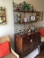 Full view of bakers rack showing wood base cabinet and metal scroll top shelving with decorative items removed.