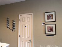 Two metal wine racks mounted vertically on the wall and two framed cafe-themed wall art paintings displayed nearby.