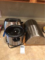 Photo of stainless steel toaster, crock pot, and bread container on countertop showing front and side of each item.