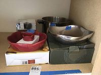 Photo showing four items: red ceramic serving bowl with pestle holder inside, metal serving bowl with curved edges, metal cooking pot with handles, and boxed Adelsten mortar and pestle.