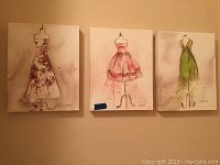 Three canvas wall art prints showing dress form designs in different colors, signed Uhmur.