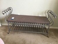 Front and top angle view of the metal bench with brown cushion and curled metal armrests.