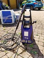 Full view of AR Blue Clean 383 power washer with hose reel and spray wand, placed on stone pavers outdoors.