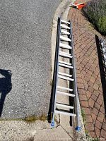 Photo showing full length of the ladder on pavement and brick surface.