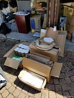 Pile of boxes and packing materials including cake boxes, napkins, tape, and cake stand.