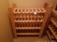 Front view of the wooden wine rack showing multiple slatted shelves for storing bottles.
