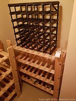 Two wooden wine racks stacked, the larger with natural wood finish and multiple wine bottle compartments, showing some wear and scratches.