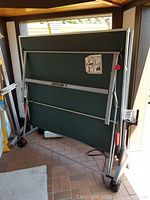 Folded ping pong table in storage area showing overall condition and folding mechanism