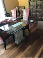 Clear glass rectangular table top placed on decorative pillars, showing its size and rounded corners.