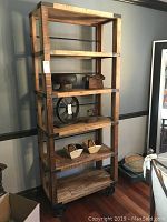 Front view of the tall wood shelving unit with metal accents and items on shelves