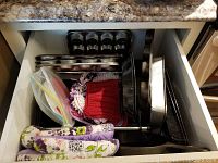 Overhead photo of drawer with various baking items including pans, oven mitts, and silicone mat bags.