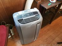 Full view of gray portable air conditioner unit with exhaust hose connected