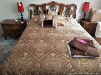 Full bed with carved headboard, comforter, pillows and side tables