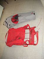 Snowshoes poles inside gray carrying bag and red aluminum framed backpack on floor
