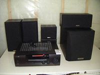 Photo showing the surround sound system components including the Kenwood VR-357 AV surround receiver, 6 speakers, and powered subwoofer arranged on a shelf.
