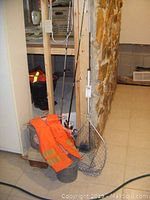 Two fishing poles with open face reels, orange life jacket, fishing net, and vintage metal Old Pal bait bucket grouped together