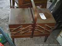Top view of closed vintage wooden sewing stand with handle and numbered tag.