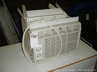 Front and side view of white Mainstays window air conditioner with removable side panels and control dials visible.