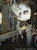 Side view of the Sears 4 HP boat motor mounted on a wooden beam showing the overall condition and mounting clamps.