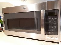 Exterior front view of stainless steel over-the-range microwave with closed door and control panel