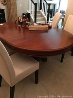 Top and side view of medium brown wooden oval dining table with extension leaf attached, showing smooth surface and light wear.