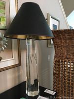 Full view of tapered clear faceted glass lamp base with black and gold lampshade on top, showing approximate height and style.