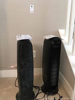 Two black vertical Honeywell air purifiers side by side with manuals on top and next to them, plugged in but untested.