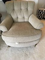 Front view of beige upholstered armchair showing tufted back and rolled arms