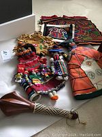 Collection showing dolls, leather pouch, placemats, and carved rattle