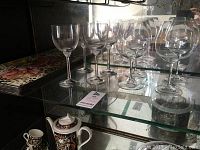 Four Villeroy & Boch crystal wine glasses and four Riedel red wine glasses displayed on a glass shelf.