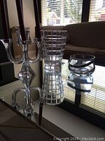 Front and side view of Nachtmann crystal vase, glass ice bucket and Villeroy & Boch candelabra on reflective glass table