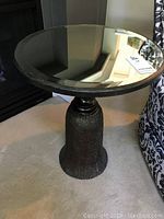 Full view of the pedestal side table showing the round mirrored glass top and tassel-shaped base with rope texture.