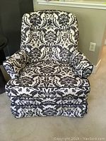 Front view of arm chair showing detailed damask pattern upholstery and cushioned seat and arms.