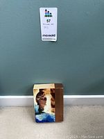 Small 5x7 block art piece against a gray wall with lot label above it.
