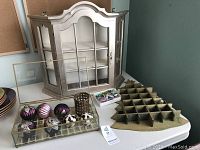 Silver display cabinet with glass door, wooden Christmas tree-shaped shelf, tray with Christmas ornaments, candle holders, and cookie cutters on table