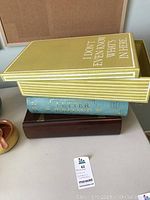 Stacked view of three decorative boxes: light green book-style box on top, blue book-style box in middle, dark brown wooden box at bottom