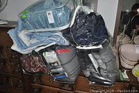 Photo showing two packaged bedding sets in plastic storage bags containing comforters and duvet covers, placed on a wooden dresser.