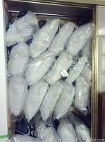 15 Blue Whale pillows sealed in plastic bags, stacked inside a closet