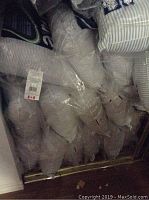 Photo showing multiple striped pillows individually wrapped in clear plastic bags packed together.