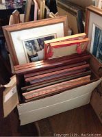 A carton filled with multiple assorted frames of various sizes and styles, wood and other materials