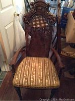 Front view of a Victorian style wooden dining chair with cane back and floral striped upholstered seat.