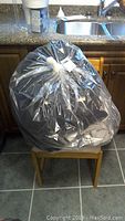 Closed large black bag of clothing as packed for sale.