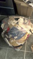 Photo showing a large clear plastic bag packed with new ladies bras and underwear in various colors including blue, gold, beige, black, and patterns, all with attached tags.