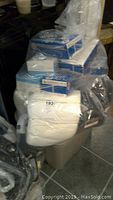 Plastic bag full of white socks in bulk packaging beside boxes.
