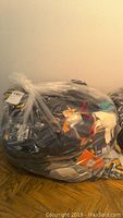 Bag containing various new work gloves in clear plastic wrapping